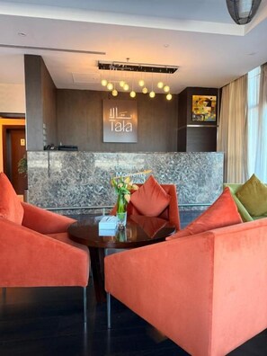 A modern hotel lobby with a reception desk, a seating area with two sofas, and a decorative wall with a sign. - Hotel Al Shahba Jeddah   (Jeddah)