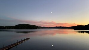 Un lac paisible au crépuscule, avec une jetée qui s’avance sur l’eau.