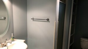 Une salle de bain avec un lavabo blanc, un miroir, une douche avec une porte en verre et des toilettes.
