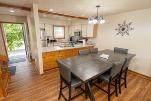 A modern kitchen with wooden cabinets, a central island, and a dining area with a table and chairs. - Family and pet-friendly, 2 Bedroom, 2 Bath, private townhome with wood-burning fireplace and jacuzzi tub (East Stroudsburg)