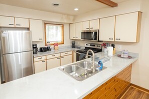 A compact kitchen with a stainless steel refrigerator, microwave, stove, and sink. - Family and pet-friendly, 2 Bedroom, 2 Bath, private townhome with wood-burning fireplace and jacuzzi tub (East Stroudsburg)