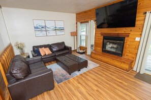 A living room with a sofa, ottoman, and fireplace.