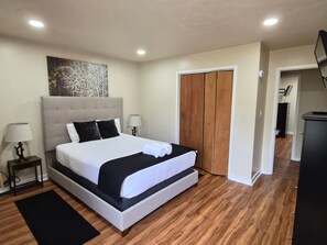 Un dormitorio con cama, mesita de noche, lámpara, cuadro, armario y escritorio.