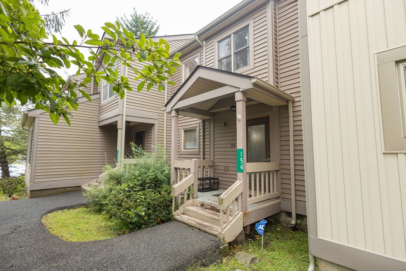 A two-story building with a covered porch and a small front yard.
