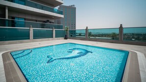 Ein Dachpool mit Delphin-Motiv, umgeben von modernen Gebäuden und einem klaren Himmel.