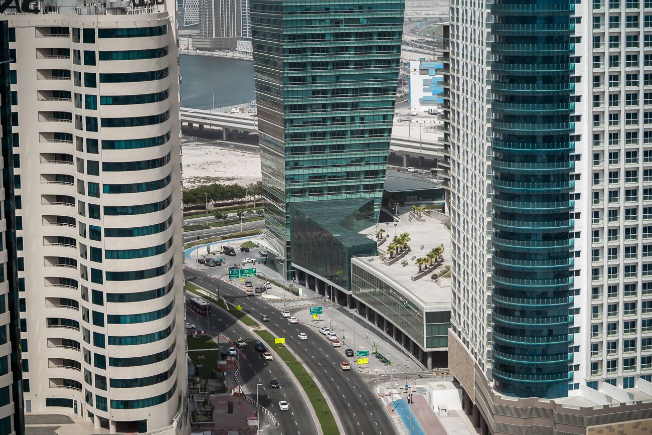 Un área urbana moderna con edificios altos, una avenida de múltiples carriles y una masa de agua.