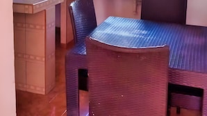 A compact kitchen with a window, a sink, and a dining area with chairs. - Hotel de Arnold (Mazatlán)