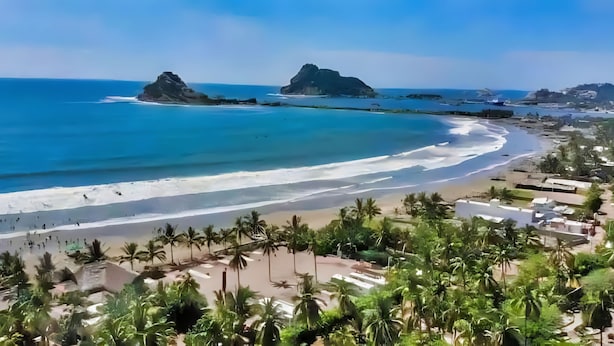 A coastal beach with clear waters, palm trees, and a sandy shore. - Hotel de Arnold (Mazatlán)