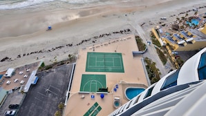 Vista aérea de un resort frente a la playa, con cancha de tenis, piscina y acceso directo a la orilla.