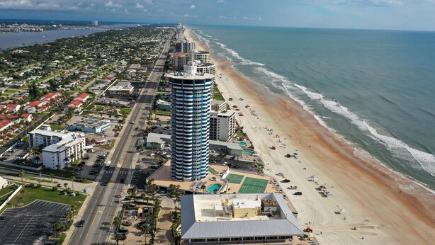 Eine Küstenstadt mit einem markanten Hotel-Hochhaus, einem Strand und freiem Blick auf den Ozean.