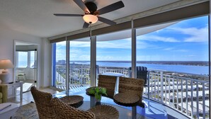 A balcony with a glass table, wicker chairs, and a ceiling fan. - SEASHELL SERENADE-24th Floor Ocean/River View - POOL, HOT TUB, Peck Plaza 2B/2B (Daytona Beach)