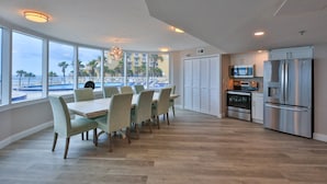 A spacious kitchen with modern appliances, large windows offering a view of the beach, and a dining area with a table and chairs. - SAND CASTLE-Amazing Ocean Views,  Pool & HotTub PeckPlaza 23NW (Daytona Beach)