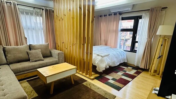 Una sala moderna con sofá, mesa de centro, cama y un separador de madera.