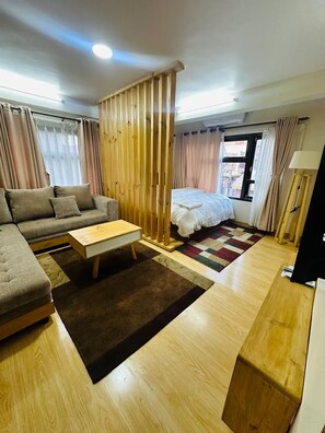 A modern living room with a sofa, a coffee table, a bed, and a wooden partition.