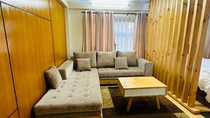 Una sala de estar moderna con un sofá modular, piso de madera, una mesita de madera y un separador de madera.