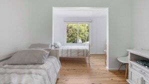 A bedroom with a bed, a desk, and a window with a view of trees.