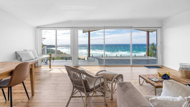 A spacious room with a large sliding glass door leading to a balcony with a view of the ocean.