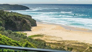 A coastal landscape with a beach, cliffs, and ocean waves.