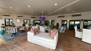 A spacious indoor area with multiple seating arrangements, including sofas and chairs, and a ceiling fan.