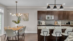 Uma cozinha moderna com armários de madeira escura, uma ilha central com banquetas e iluminação pendente.