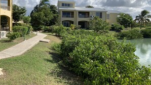 Ein zweistöckiges Haus mit Balkon, gepflasterter Auffahrt und Teich im Vordergrund.