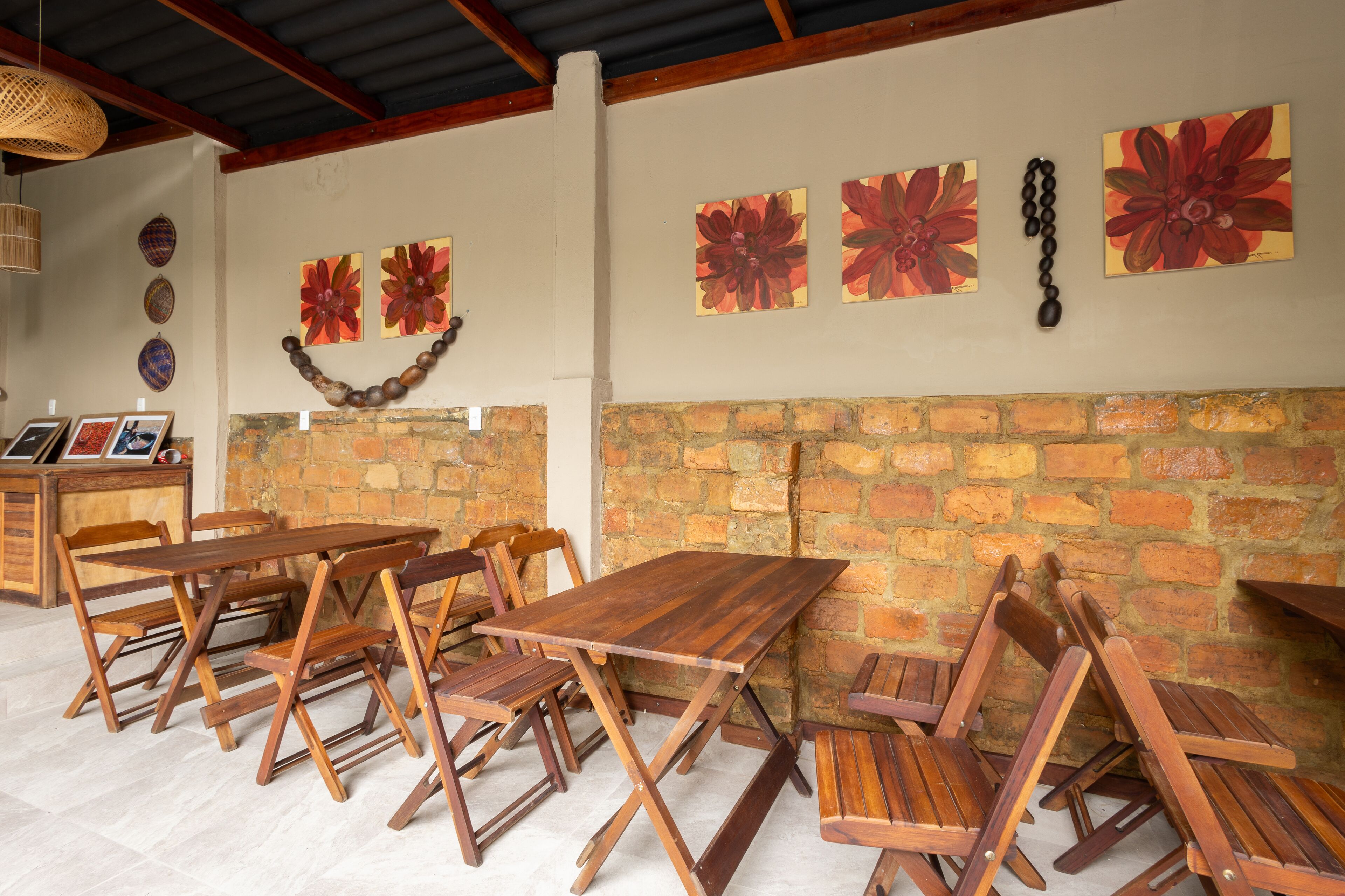 A rustic dining area with wooden tables and benches, a brick wall, and decorative wall art.