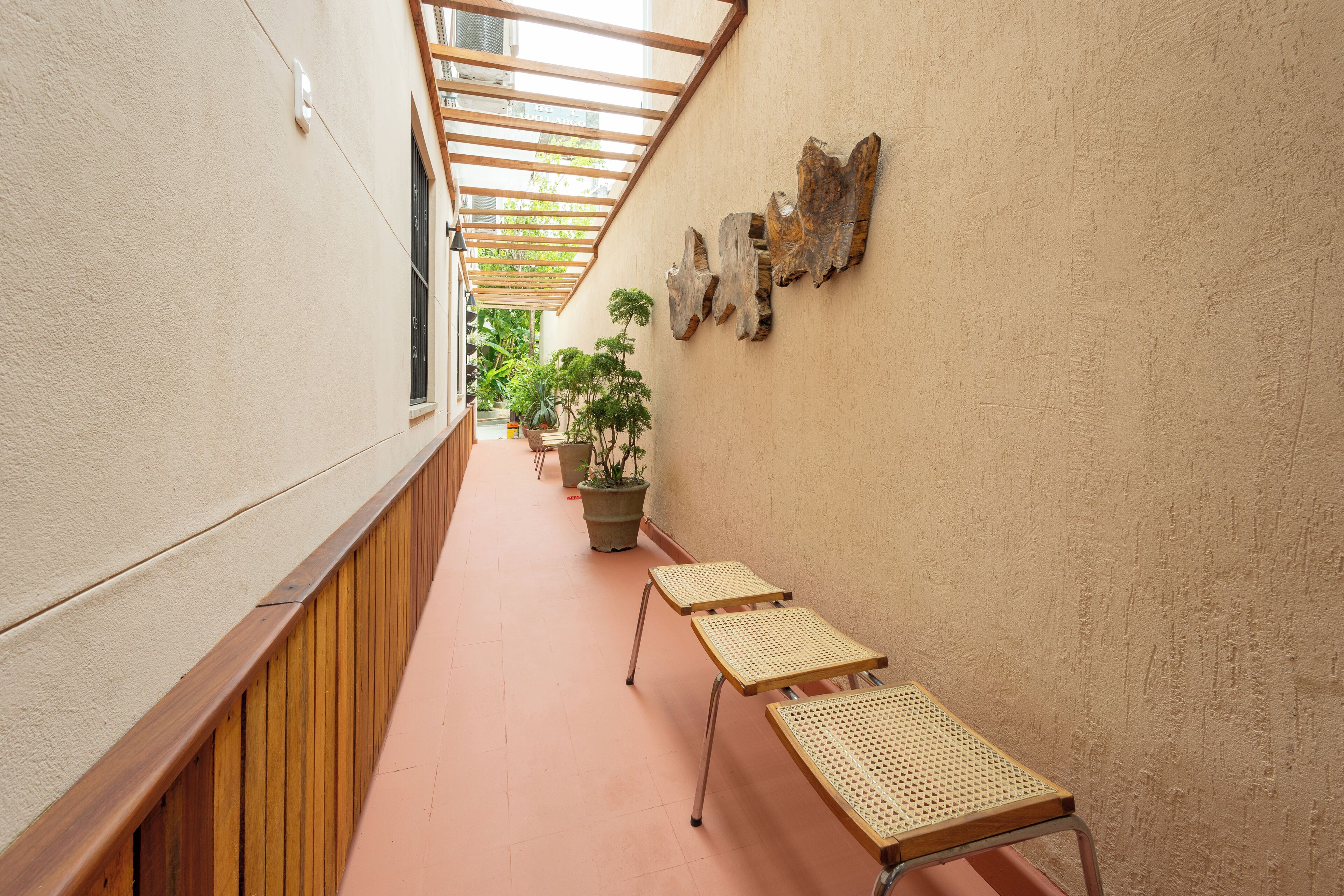 Un pasillo con bancos de madera, plantas en macetas y obras de arte en la pared.