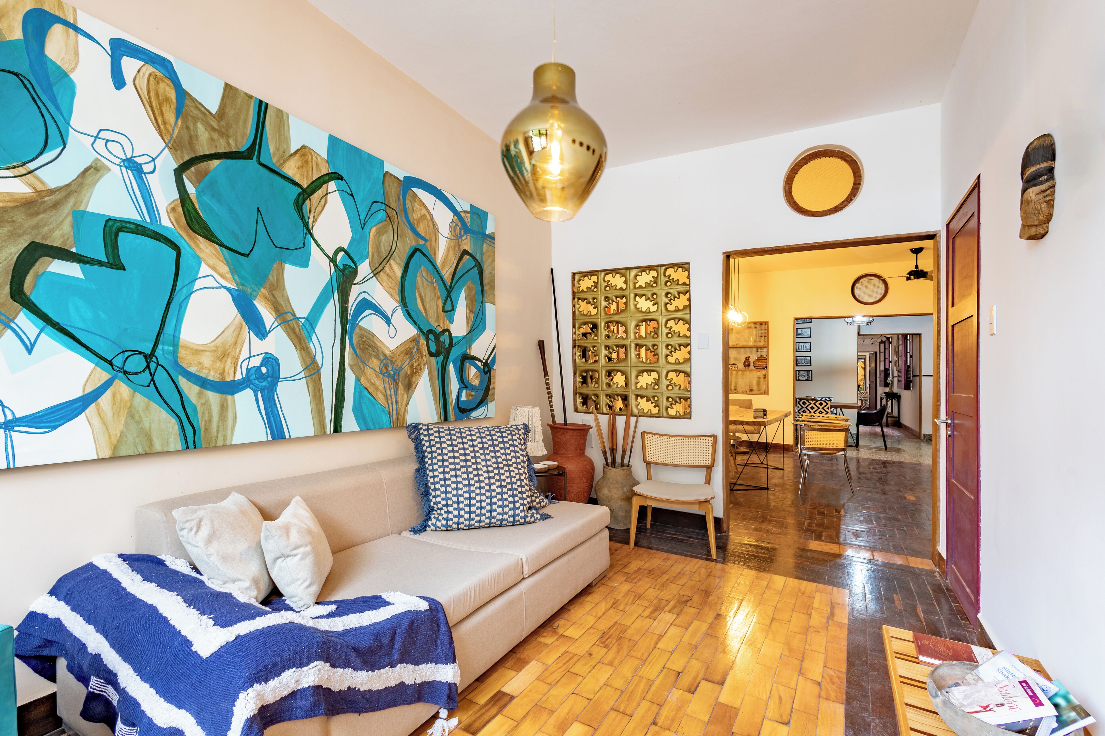 A living room with a sofa, a large abstract painting, and a wooden floor.
