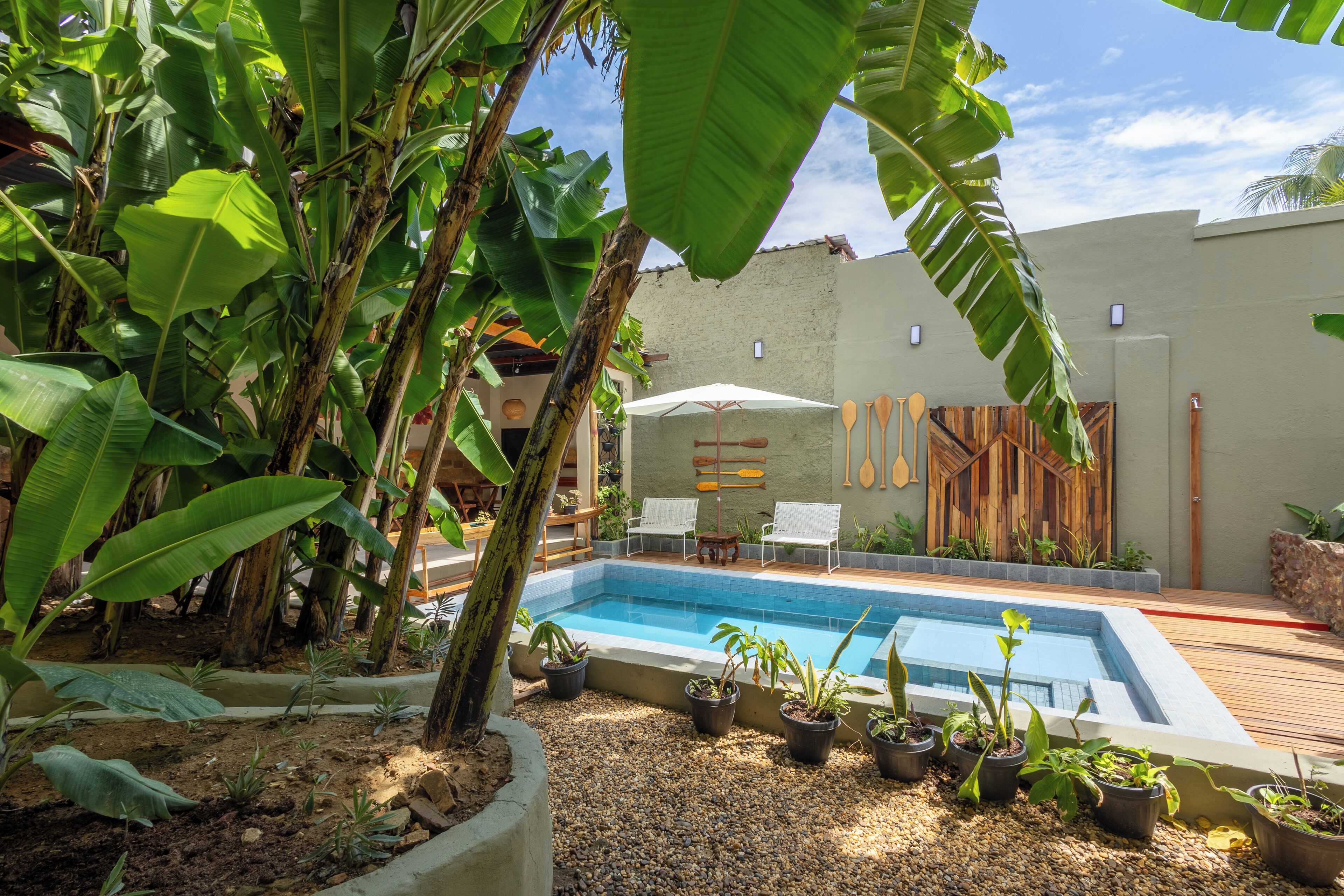 A swimming pool surrounded by potted plants and a wooden deck.