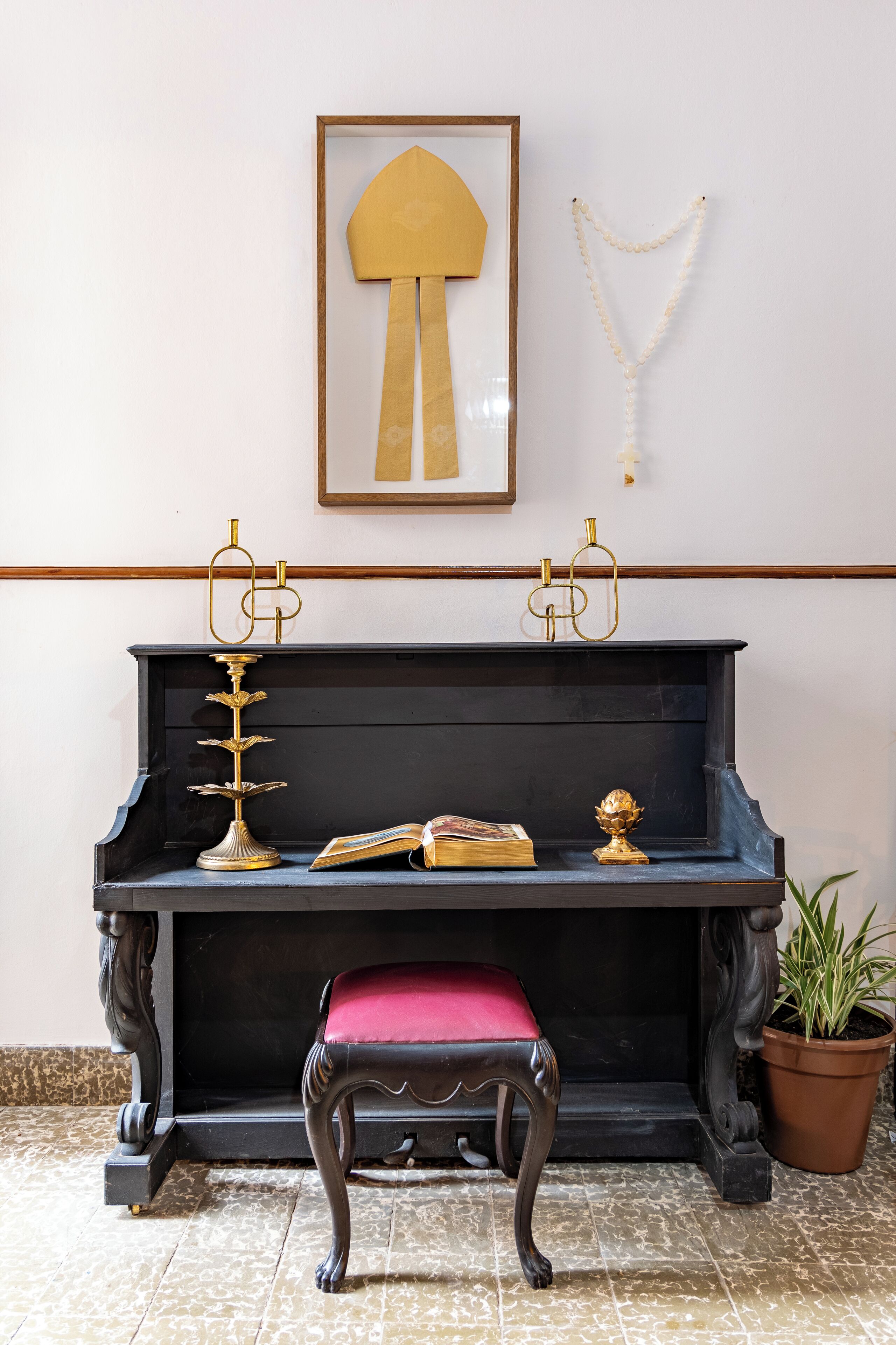 A piano with a red cushioned bench, a gold decorative item, and a book on top.