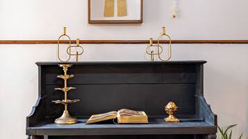 A piano with a red cushioned bench, a gold decorative item, and a book on top.