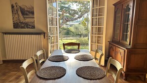 Comedor con mesa para cuatro, un radiador, un armario y vistas a un jardín.
