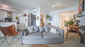 Una sala de estar moderna con un sofá gris, un sillón de cuero marrón y una zona de comedor con mesa de madera.