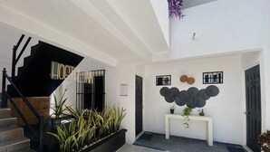 A modern hotel entrance with a staircase, a sign reading "HOSTEL INN," and a wall decorated with circular wall art. - The Hostal Inn (Playa del Carmen)