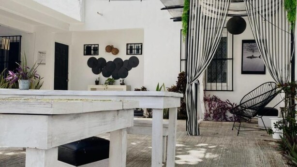 A modern interior with a white table, black and white striped curtains, and a black chair. - The Hostal Inn (Playa del Carmen)