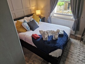A neatly made bed with a blue blanket, multiple pillows, and a red gift box. - Charming 1-bed Studio, Parking, Kitchen,wifi (Hampton)