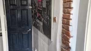 A hallway with a black door, a wall-mounted poster, and a brick accent wall.