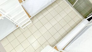 A room with a tiled floor, white furniture, and a window with a view of the outside. - SJO Oasis Hostel (San José)