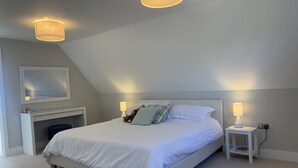 Ett välordnat sovrum med en stor säng, två sänglampor, en spegel och ett litet bord.