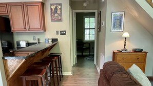 A kitchen with wooden cabinets, a bar stool area, and a dining area with a table and chairs.