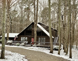 A cabin with a steep roof, a front porch, and a staircase leading to the entrance.