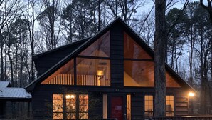 A cabin with a large front window, a red door, and a number '145' on the side.