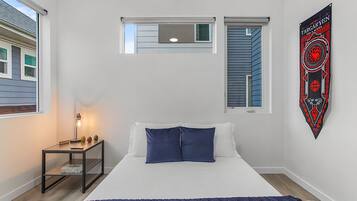 A bedroom with a bed, a nightstand, a window, and a wall-mounted banner.