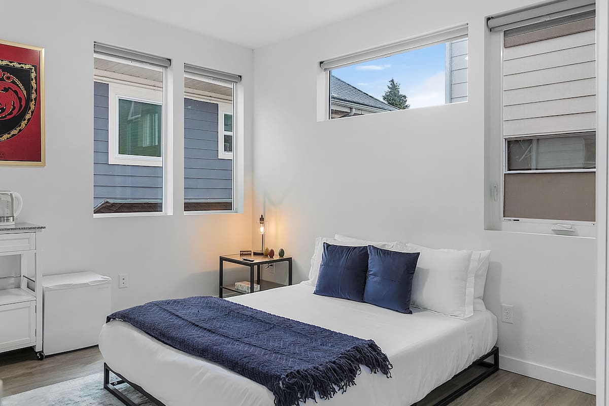 Quarto com cama, mesa de cabeceira com abajur e janela.