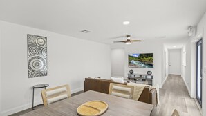 A modern dining area with a wooden table, chairs, and a ceiling fan. - Vero Beach Paradise Unit 2 - 2 BR Pool Home Close to Airport, Downtown & Beaches (Vero Beach)