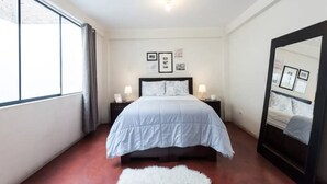 A bedroom with a bed, bedside tables, a large mirror, and framed pictures on the wall. - InkaHuset Airport (Callao)