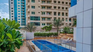 A rooftop swimming pool with a metal railing, surrounded by greenery and a multi-story building in the background. - Full Marina view - Opal Tower (Dubai)