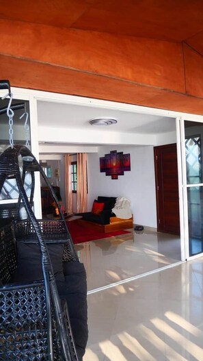 A spacious living area with a modern sofa, a decorative wall piece, and a sliding glass door.