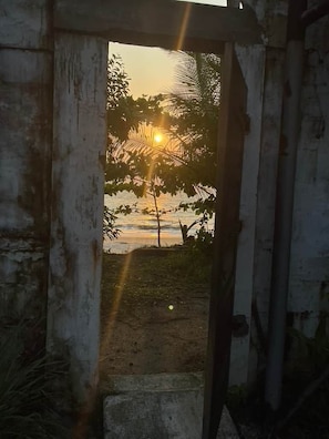 An open doorway leading to a sunset view with palm trees.