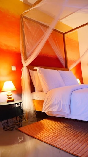 A bed with white linens, a wooden headboard, and a mosquito net.